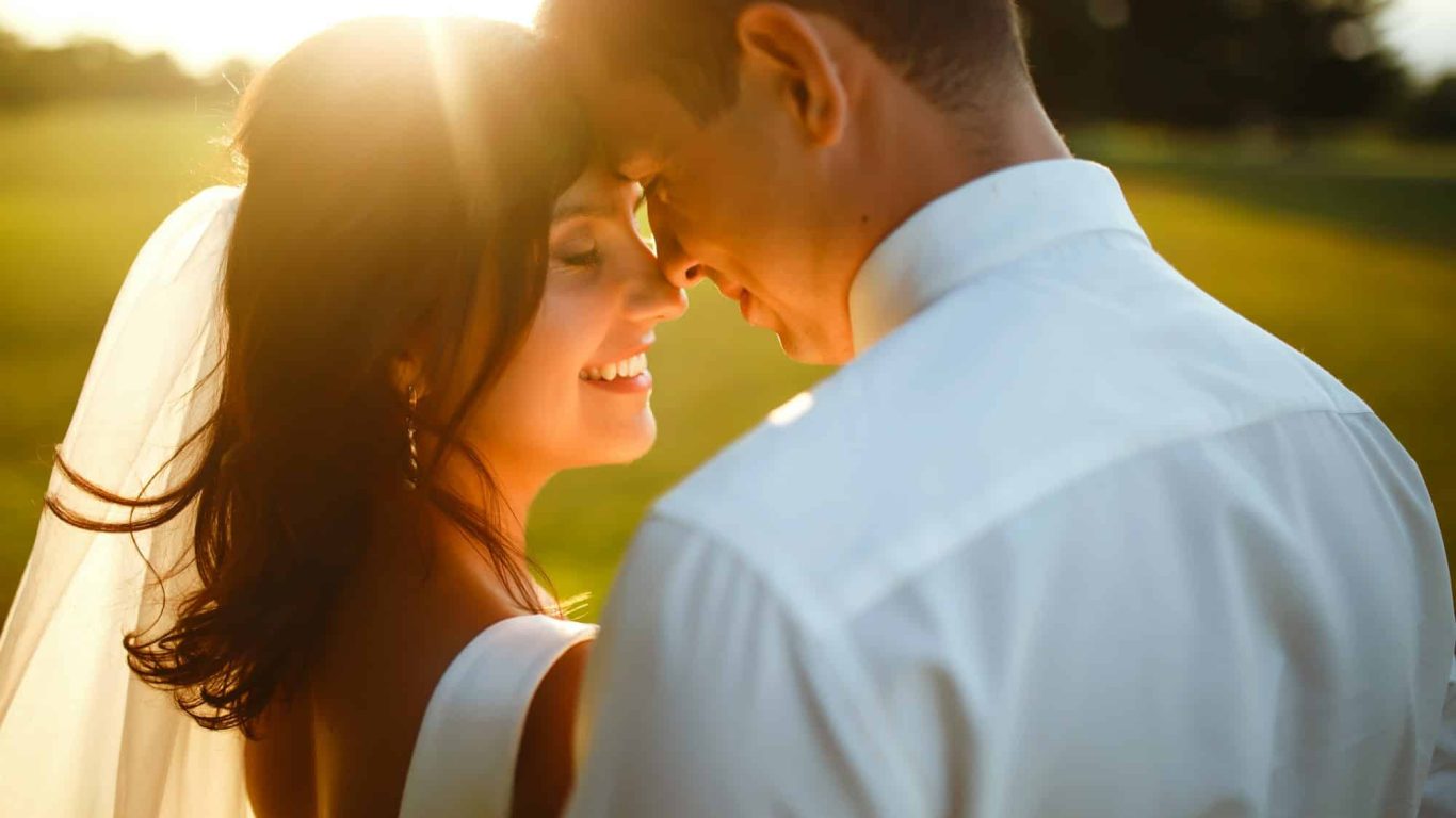 Lovely wedding couple at sunset. Bride, groom in wedding attire with bouquet of flowers. Romantic.